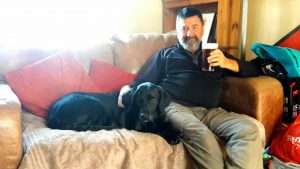 Tim on the lounge with a black labrador