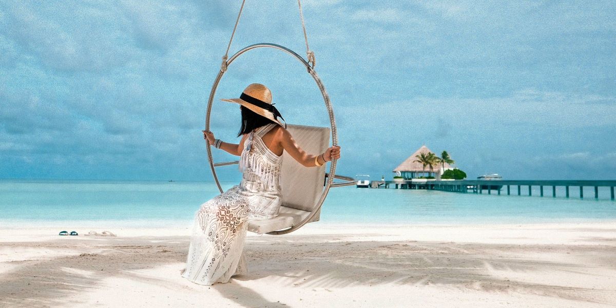 A lady on a swing on a beach in the Maldives